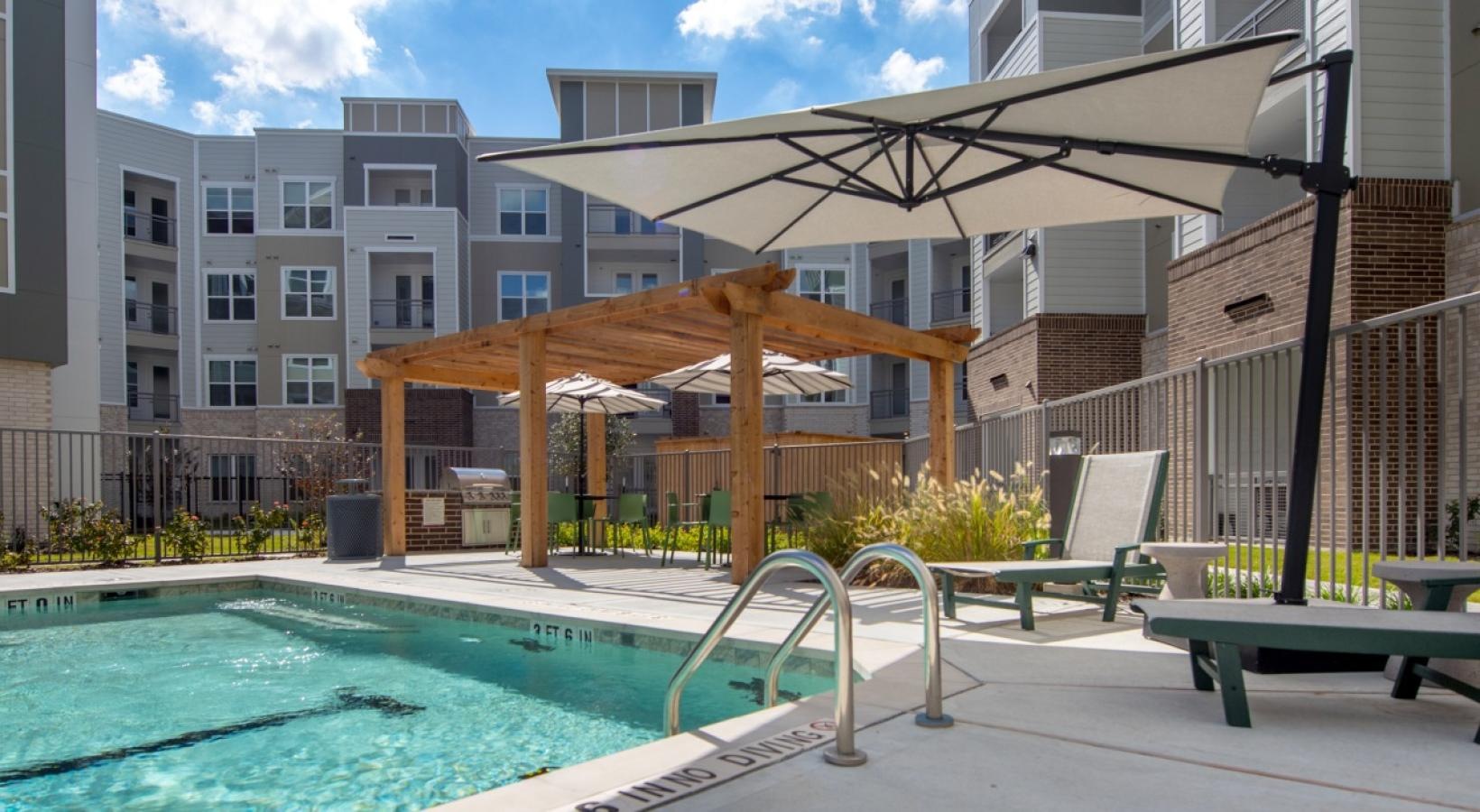 a pool with chairs and umbrellas by a building