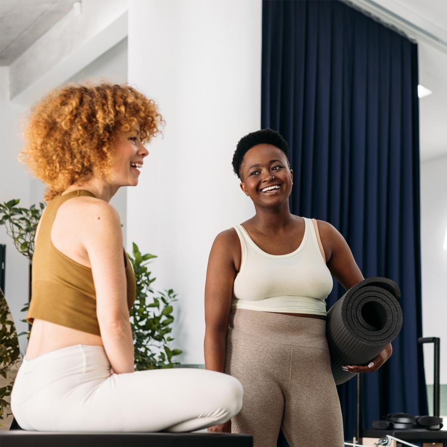 a person holding a yoga mat standing next to a person sitting on a chair